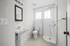 Bright, modern bathroom featuring elegant subway tiles, a sleek glass shower, and stylish pedestal sink.