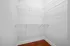 Spacious walk-in closet with sleek white shelving and elegant hardwood floors, perfect for organizing.