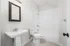 Sleek and modern bathroom featuring a fresh white subway tile bathtub, elegant vanity with a chic mirror, and pristine fixtures for a clean, sophisticated look.