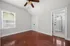 Elegant bedroom with rich wooden floors, bright window, and en-suite modern bathroom, perfect for comfortable living.