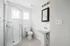 Bright, modern bathroom featuring a sleek corner shower, elegant pedestal sink, and chic subway tile walls.