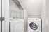Modern laundry room with sleek washer and dryer under a stylish sloped ceiling, featuring ample shelving for convenient storage.