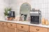 Inviting apartment coffee bar with sleek appliances, elegant backsplash, and cozy wooden cabinetry.