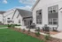 Charming modern white farmhouse-style apartment exterior with cozy outdoor seating and bright green landscaping.