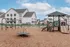Inviting community playground with modern equipment set against a backdrop of charming white residential buildings, perfect for family-friendly living.