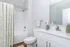 Modern bathroom with elegant white fixtures, a stylish shower curtain, and sleek vanity with polished faucets.
