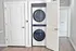 Modern apartment with a sleek, stacked washer and dryer neatly tucked behind white doors, featuring elegant hardwood floors.