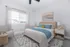 Inviting bedroom with natural light, cozy bed adorned with blue accents, and modern wooden furniture, offering a serene retreat.