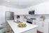 Modern kitchen with sleek white cabinetry, stainless steel appliances, spacious island with sink, and stylish seating.