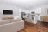 Modern kitchen with white countertops and cabinets. Living room with couch and TV