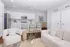Bright and modern open-concept living area with sleek white cabinetry, stylish bar seating, and cozy seating arrangements.