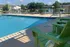 Inviting outdoor pool area with comfortable green Adirondack chairs and sun loungers, set against a serene lakeside backdrop.