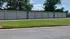 Expansive row of modern storage units with sleek rolling doors, surrounded by green lawn and lush trees.