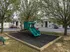 Charming apartment complex with a vibrant playground and lush trees, perfect for family living.