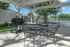 Charming outdoor patio with barbecue grill and seating, overlooking a serene lake and lush greenery, ideal for relaxing and entertaining.