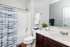 Bright and modern bathroom featuring elegant fixtures, a stylish shower curtain, and a well-organized vanity with lush greenery.