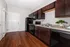 Modern kitchen with sleek dark wood cabinets, stainless steel appliances, and elegant hardwood flooring.