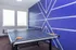 Vibrant recreational room featuring a stylish blue accent wall and a professional ping pong table with paddles, offering a perfect spot for fun and relaxation.