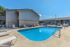 Inviting apartment complex pool area with lounge chairs under a clear blue sky, offering a perfect spot for relaxation and leisure.