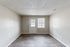Bright and airy living room with sleek wood flooring, offering ample natural light through a large window and door.