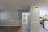 Inviting apartment hallway with elegant wood flooring leading to a modern kitchen with sleek white cabinetry and stylish backsplash.