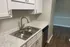 Elegant kitchen with sleek marble countertops, stainless steel sink, and modern white cabinetry creating a stylish and functional space.