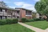 Charming apartment complex exterior featuring lush green lawns, vibrant bushes, and a modern brick facade.