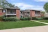 Charming apartment building with classic brick exterior, inviting balconies, and lush green landscaping.
