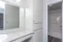 Bright, modern bathroom with white cabinetry, expansive mirror, and sleek countertop offering ample storage and style.