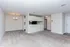 Spacious and inviting open-plan living area with plush carpeting and modern lighting, seamlessly connected to a sleek kitchen with a stylish breakfast bar.