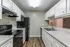 Modern kitchen with sleek granite countertops, stainless steel dual sink, and ample white cabinetry, accented by sleek black appliances and rich wood flooring.