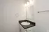 Modern bathroom with sleek countertop, chic mirror, and elegant lighting fixtures.