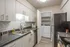 Modern kitchen with sleek countertops, stainless steel sink, and adjacent laundry room for added convenience.