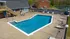 Inviting outdoor pool area with lounge chairs, surrounded by lush greenery and a serene pond view, ideal for relaxation.
