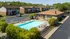 Charming apartment complex with a sparkling swimming pool, surrounded by lush greenery and ample parking.