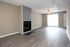 Bright and spacious living room with elegant flooring, modern fireplace, and ceiling fan, leading to a sunlit patio door.