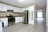 Modern kitchen with sleek stainless steel appliances, spacious white cabinetry, and open layout leading to a bright living area with laminate flooring.