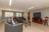 Inviting communal living area featuring comfortable leather seating, elegant glass coffee table, and large flat-screen television, perfect for relaxation and entertainment.