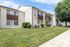 Charming two-story apartment building with a neatly maintained lawn and trees, ideal for comfortable suburban living.