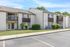 Charming apartment building with modern architectural design, featuring private balconies, lush landscaping, and ample parking space.