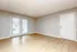 Bright and spacious living room with elegant wood flooring, large sliding glass doors, and modern neutral walls.