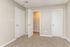 Inviting room with plush carpet and elegant neutral walls, featuring two closed doors and an open closet, perfect for spacious living.