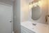 Chic bathroom with modern lighting and elegant round mirror, offering a serene and stylish ambiance.