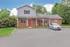 Charming brick apartment with vibrant red doors, nestled in lush greenery and featuring convenient parking.