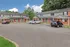 Charming townhouse community with red brick and gray siding, featuring inviting red doors and ample parking in a serene setting.