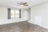 Bright living room with elegant wood flooring, ceiling fan, and large window providing natural light, perfect for comfortable living.