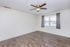 Inviting empty room featuring elegant wood flooring, a modern ceiling fan, and large window with curtains for natural light.