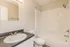 Bright, modern bathroom featuring an elegant sink with a dark countertop and a pristine bathtub for relaxation.