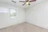Bright and airy bedroom with a neutral palette, equipped with a ceiling fan and a large window providing natural light and a pleasant view.