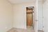 Cozy room featuring plush carpet and a white closet with a rustic wooden interior detail, ideal for convenient storage solutions.